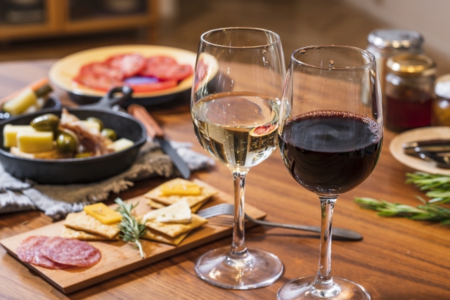 赤ワインと白ワインのグラス、チーズやサラミなどのおつまみが並ぶテーブル