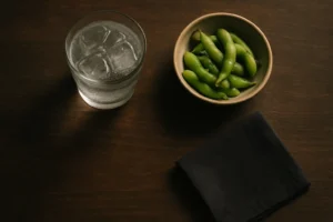 和の器に注いだ透明な炭酸の飲み物と小鉢のおつまみを真上から見た卓上