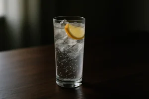 氷とレモンスライスを入れた炭酸のグラスが木のテーブルに置かれている